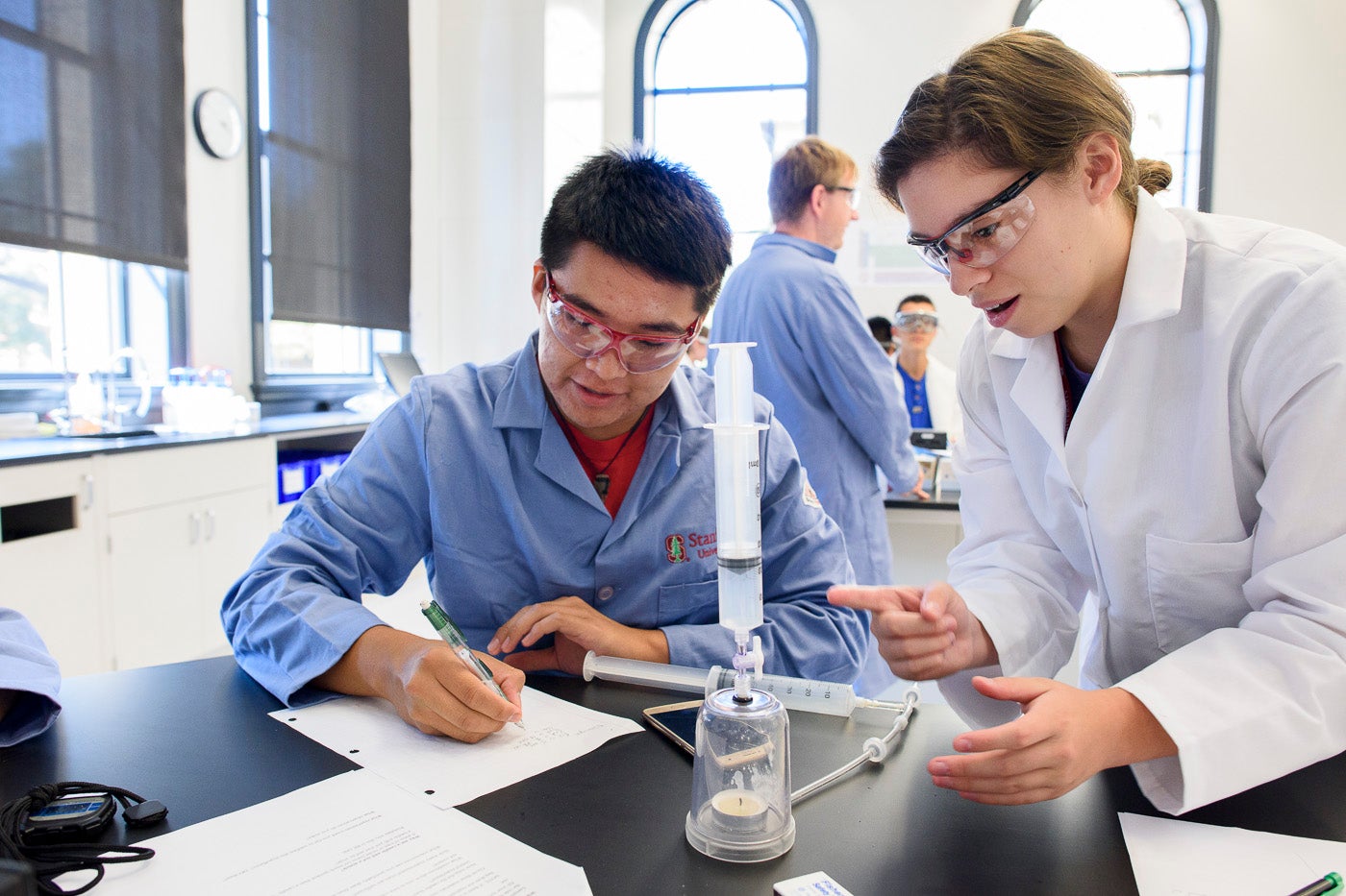 Leland Scholars Ely Jay Nez and Lizbeth Gomez observe changes in a lit candle after introducing nitrogen into a sealed jar.