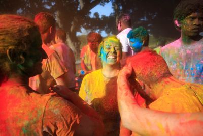 Student covered in colored dust, smiling.