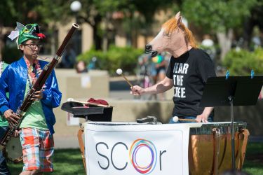 two orchestra members perform in colorful costumes
