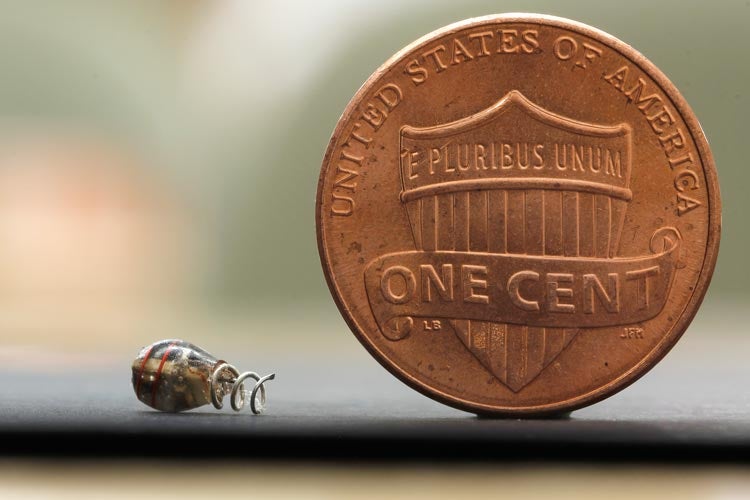 tiny implant to monitor health or deliver therapies inside the body; shown next to penny for scale