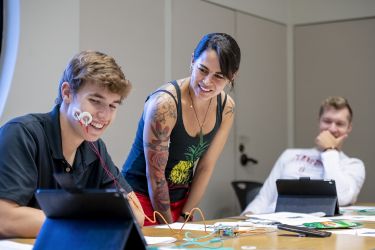 First-year Stanford student Karsten Householder observes the electrical impulses generated by his smile on an iPad – with the help of a pair of electrodes attached to his cheek – during a class meeting of “How Does Your Brain Work,” taught by Lecturer Lupita Ruiz-Jones, (center), who earned a PhD in marine biology at Stanford and is also an alumna of its Diversifying Academia, Recruiting Excellence Doctoral Fellowship Program.