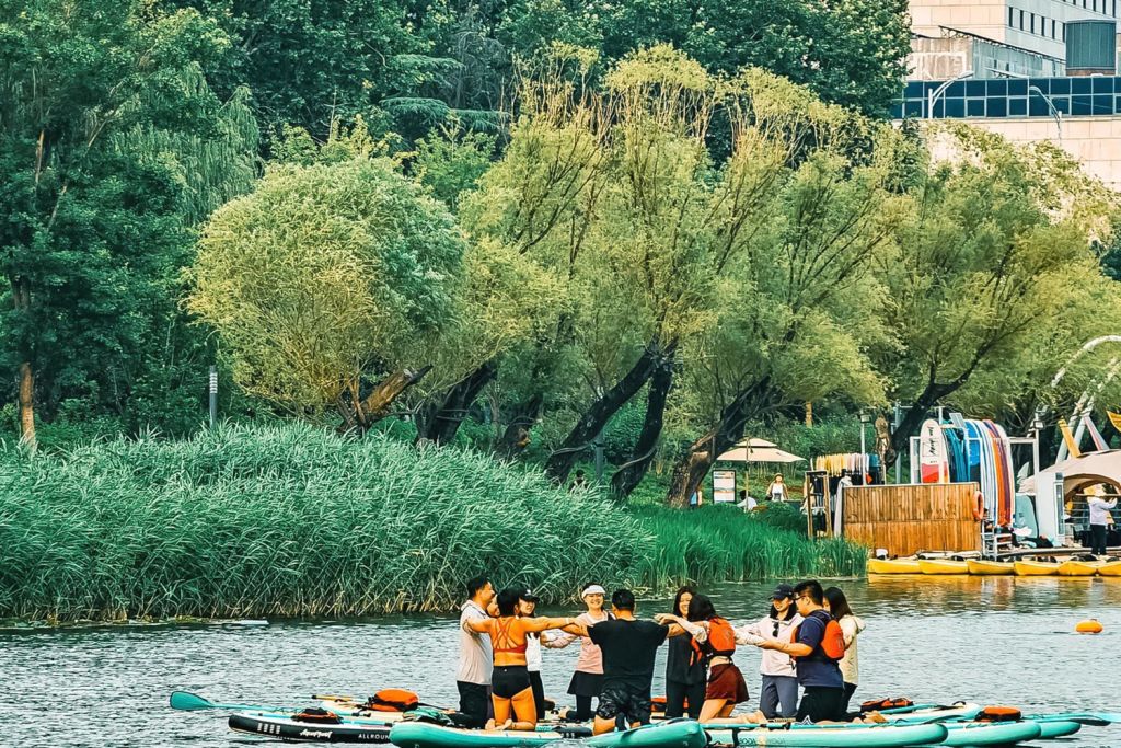Image of people enjoying water activities on a lake located near a city.