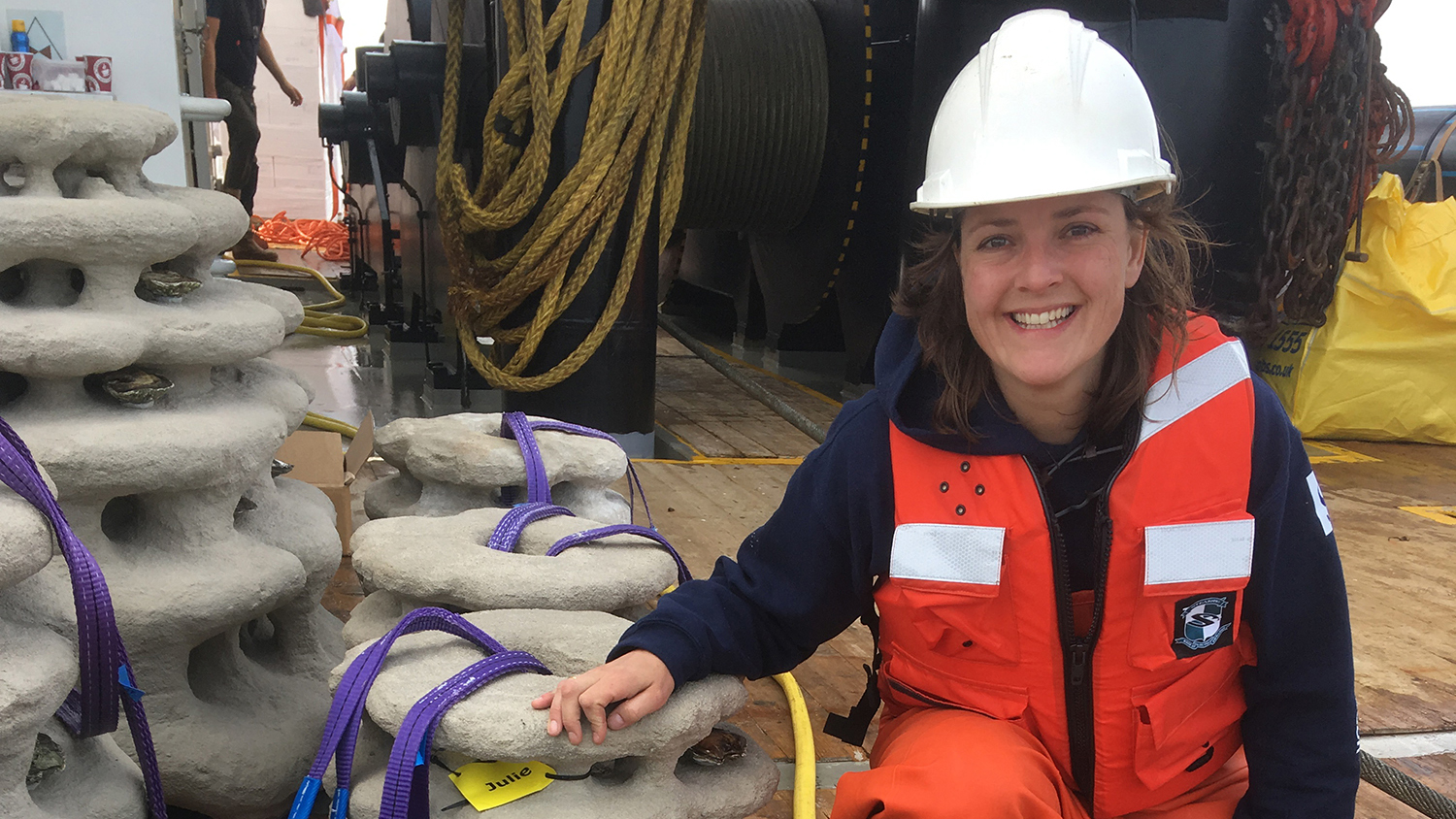 Image of Emilie Reuchlin on a boat wearing a hard hat and safety vest.