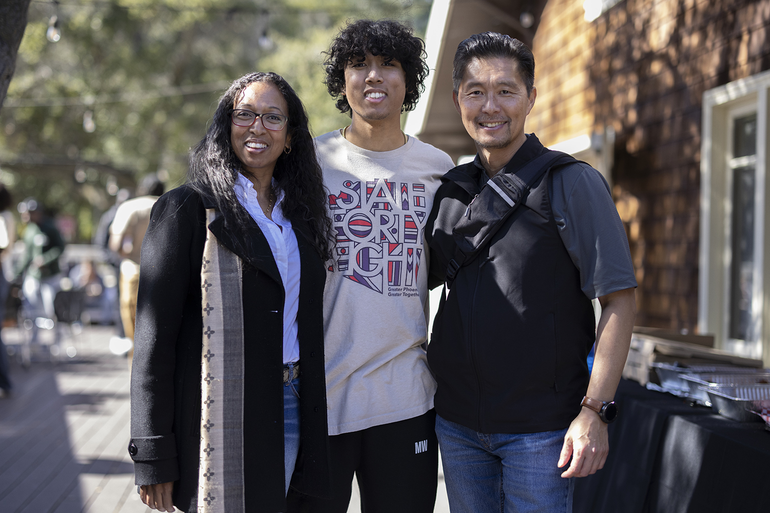 A students poses for a photo with his parents on the Stanford campus during Family Weekend.