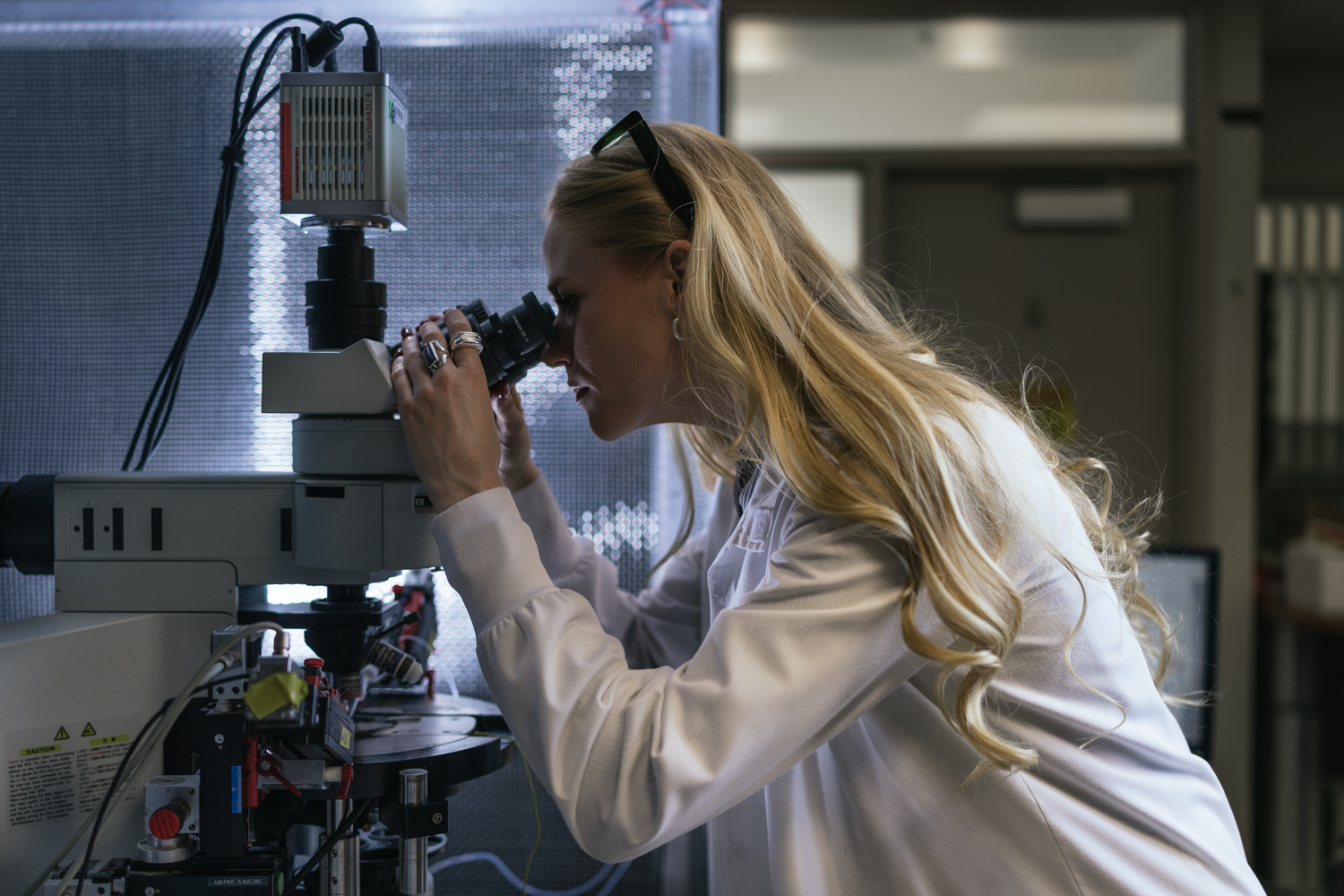 Scientist Annie Goettemoelle observes samples closely through a microscope in a laboratory setting.
