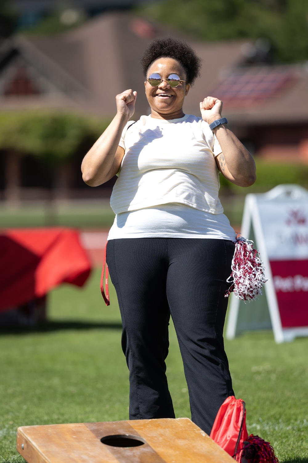 A person celebrating during a game of cornhole at an outdoor event.