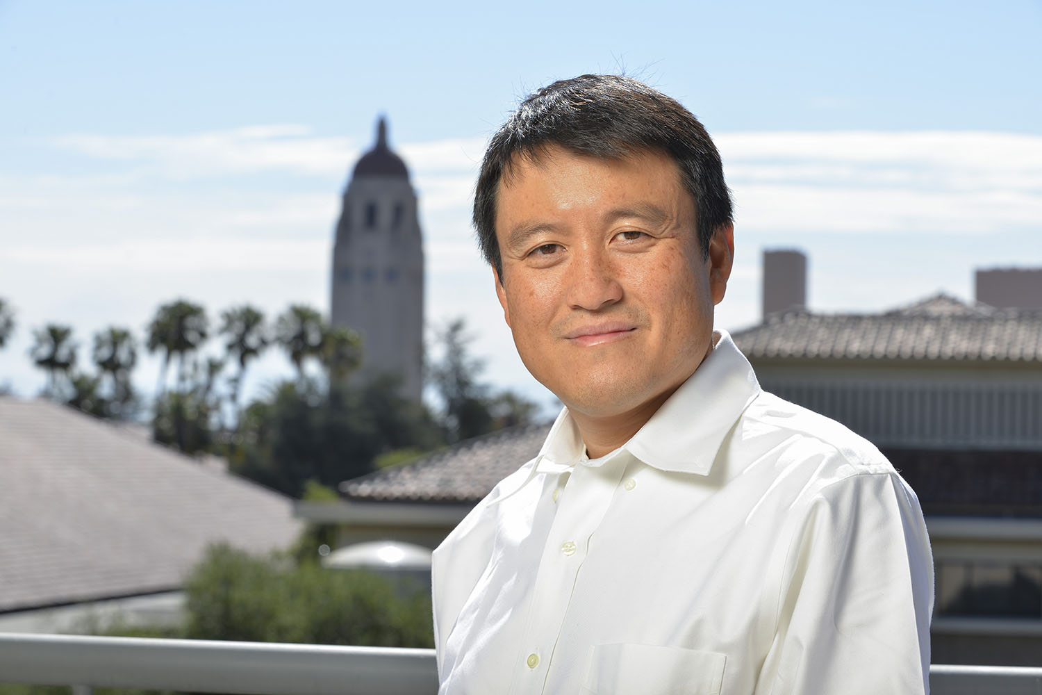 Shanhui Fan in white shirt with Hoover Tower and palm trees visible in the background.