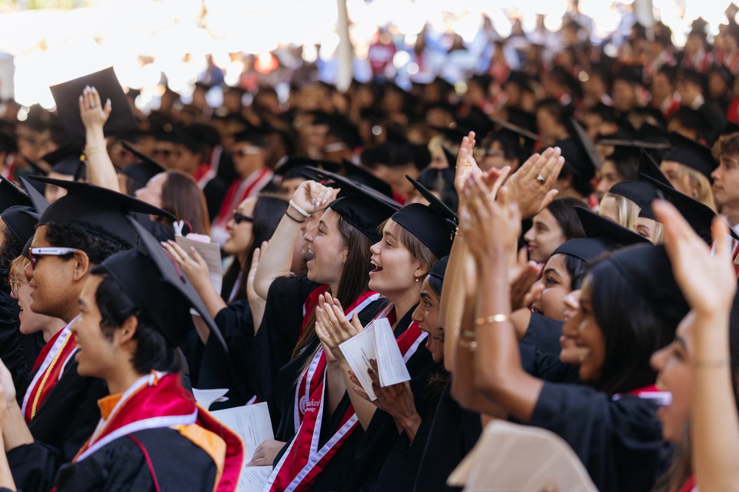 Graduates in caps and gowns enthusiastically applaud during Baccalaureate.