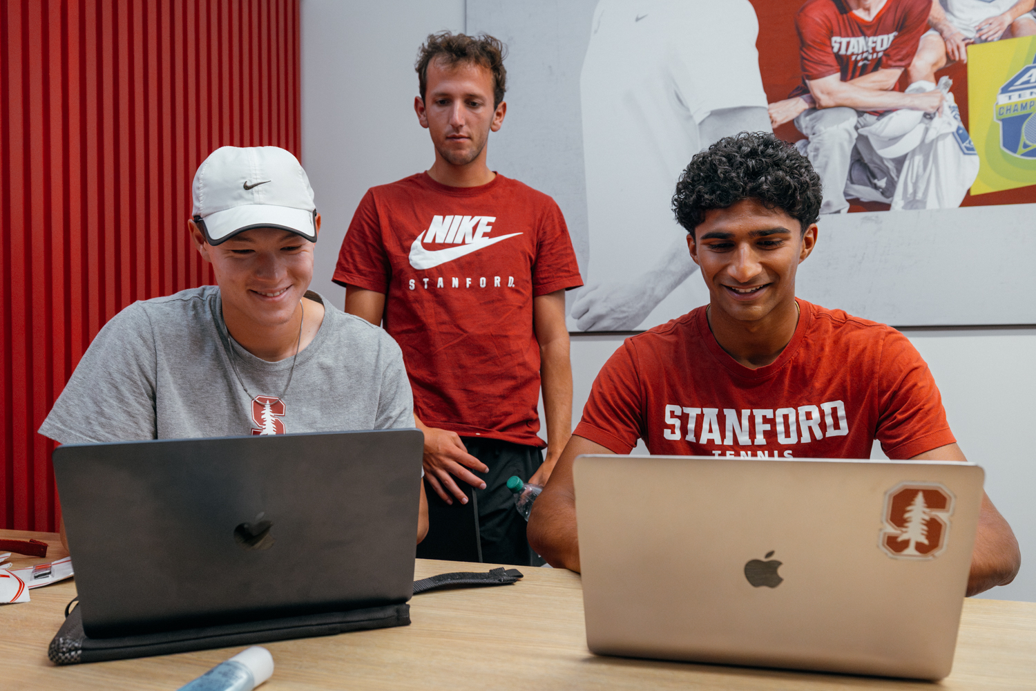 Samir Banerjee sits at a table with two of his friends, working together with their laptops.