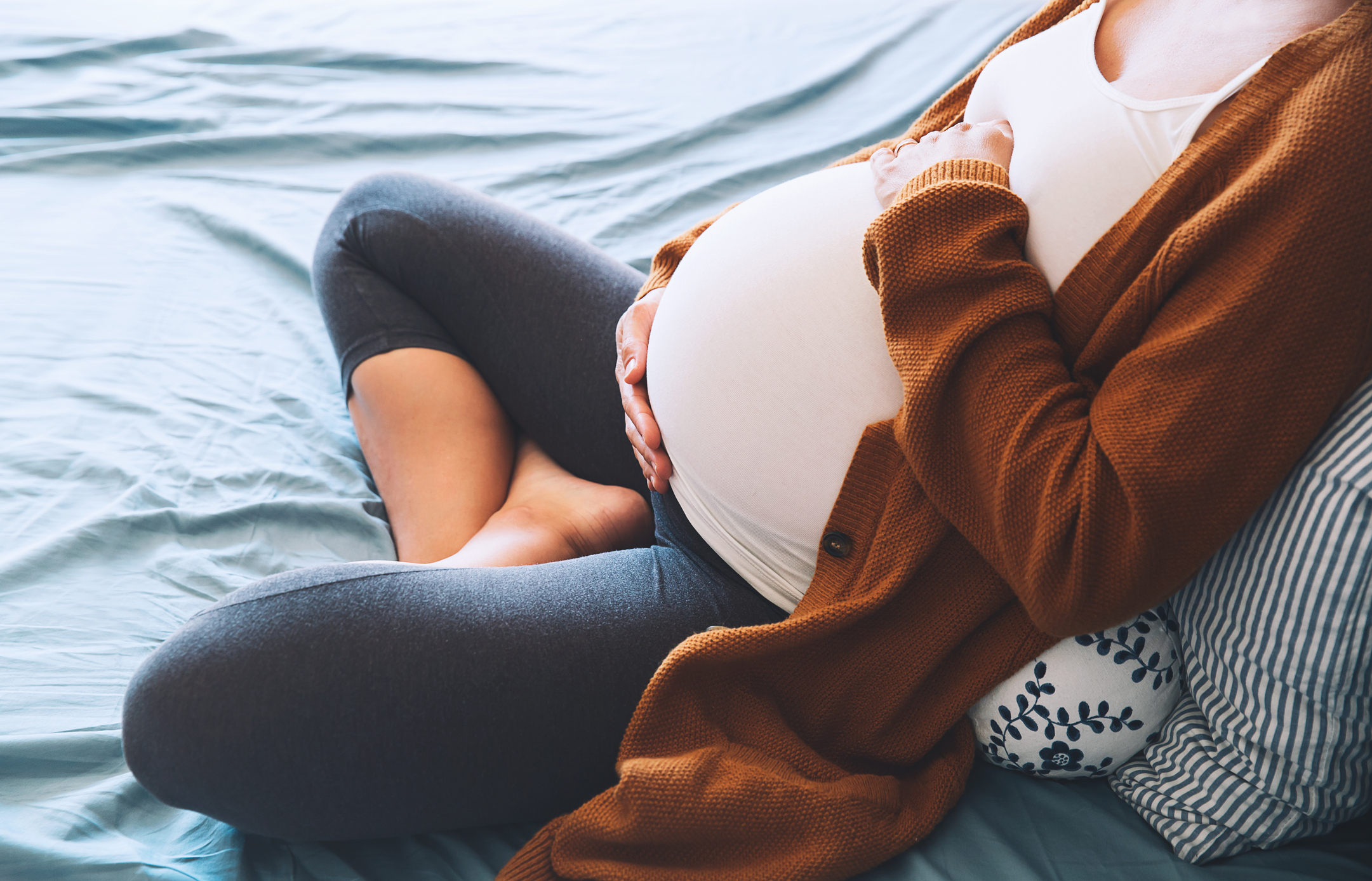 Pregnant woman on bed, holding her belly