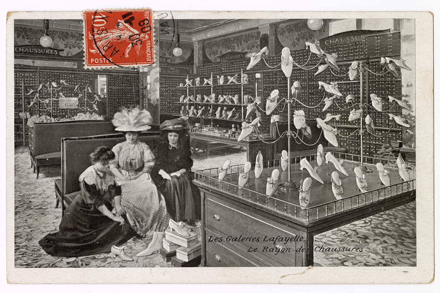 A vintage postcard depicts women shopping for shoes in the Galeries Lafayette department store.