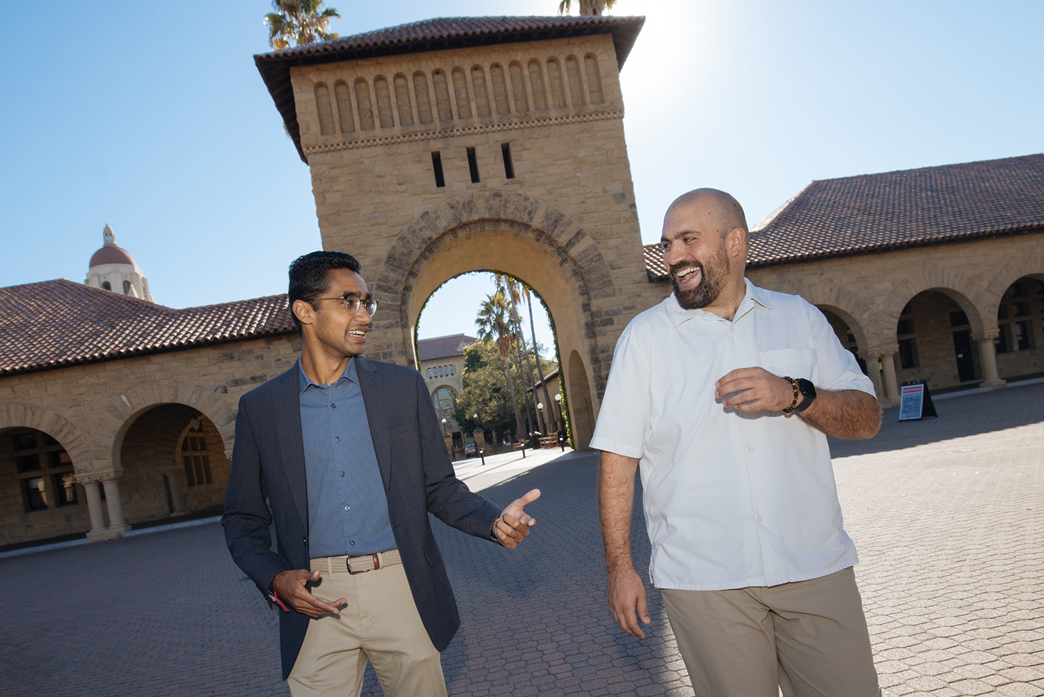 Ronak Vyas and Micky Chahcoi talk and laugh while walking across the Quad on the Stanford campus.