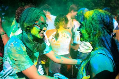 Students covered in colored dust, smiling.