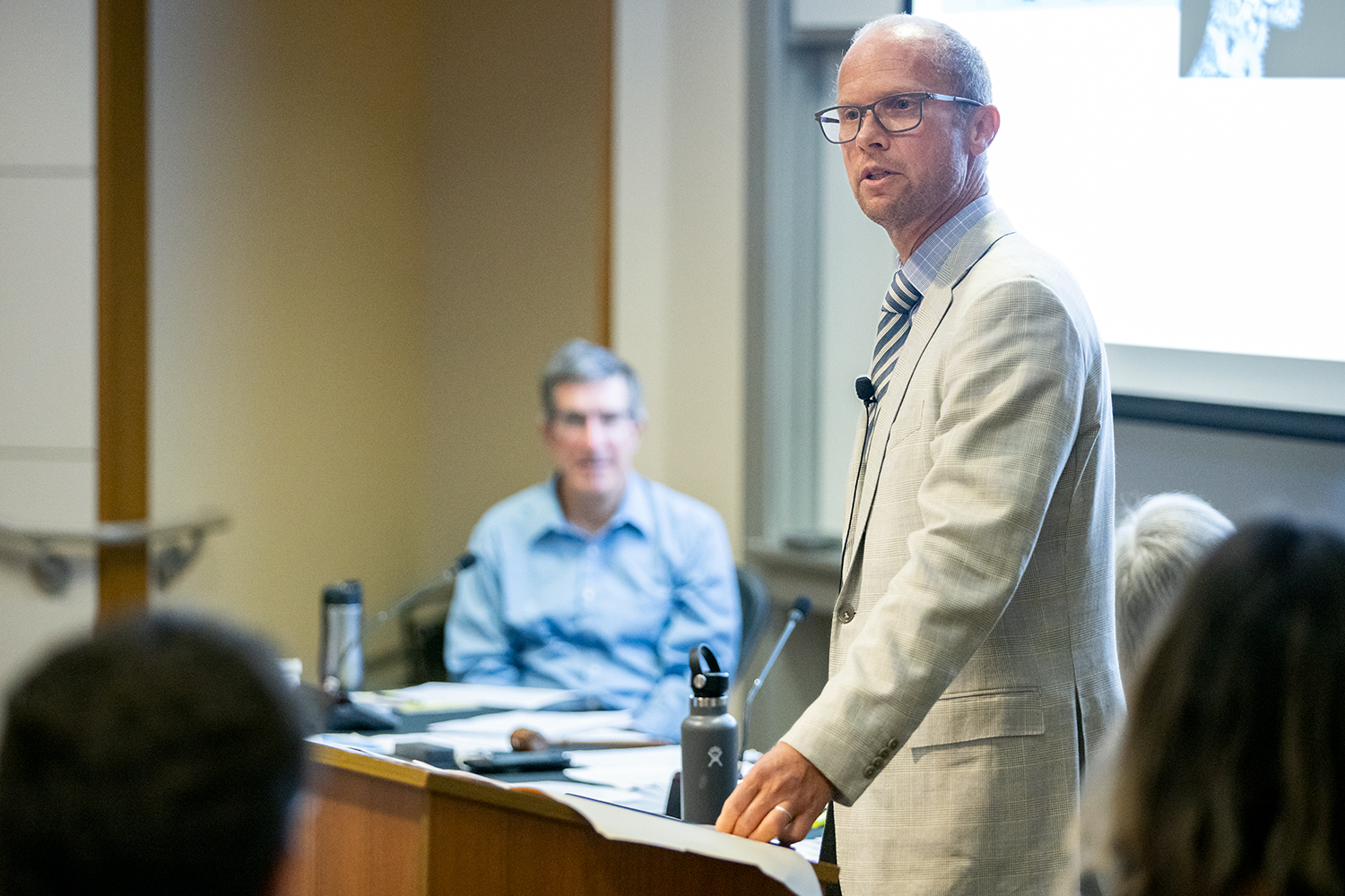 A side profile of Norman Spaulding standing at a podium and speaking to the Faculty Senate.