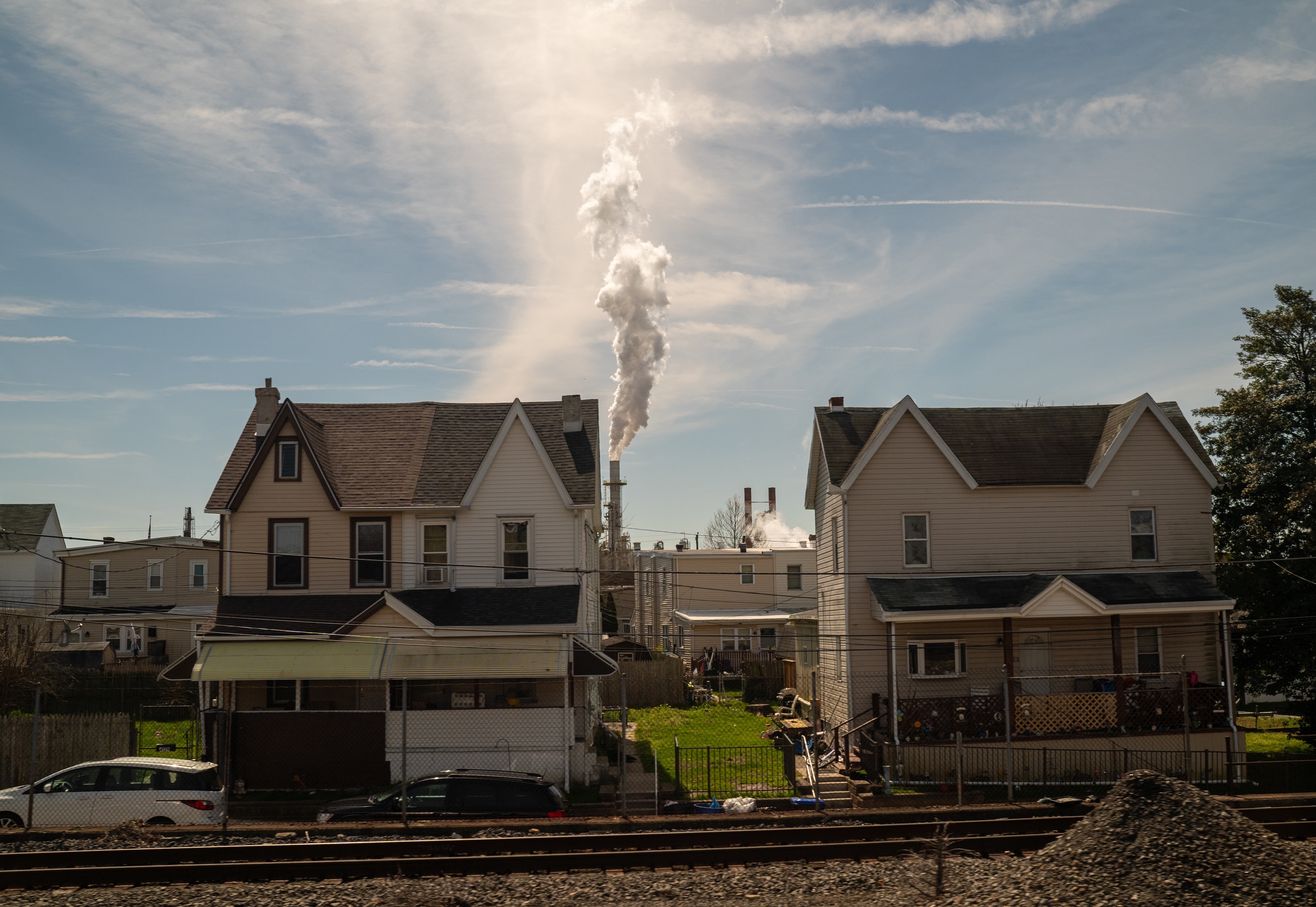 Industrial smokestack behind homes and a railroad track
