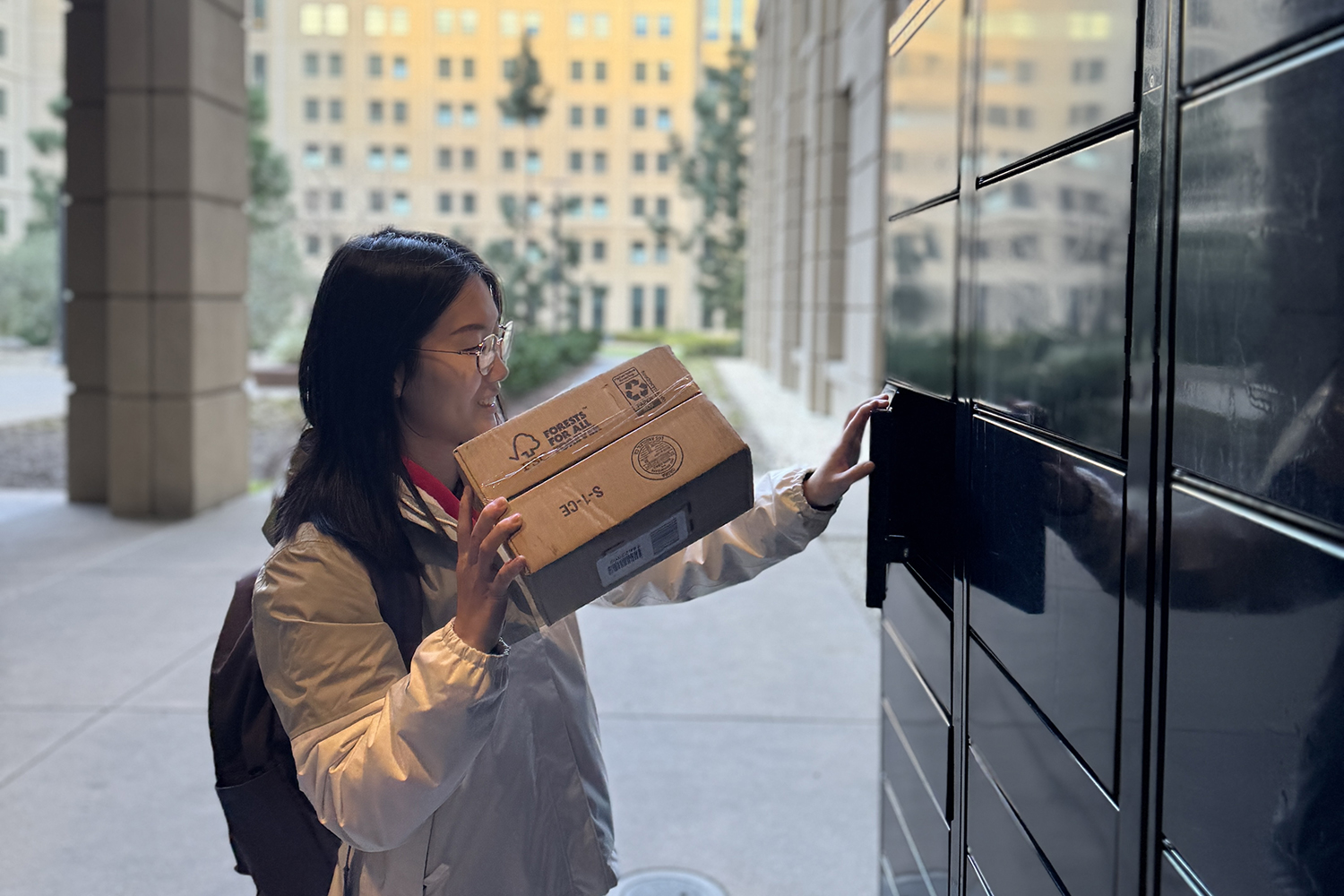 Image of Living Lab fellow Yuan Molly Tian opening a locker and picking up a delivery from a campus package center.