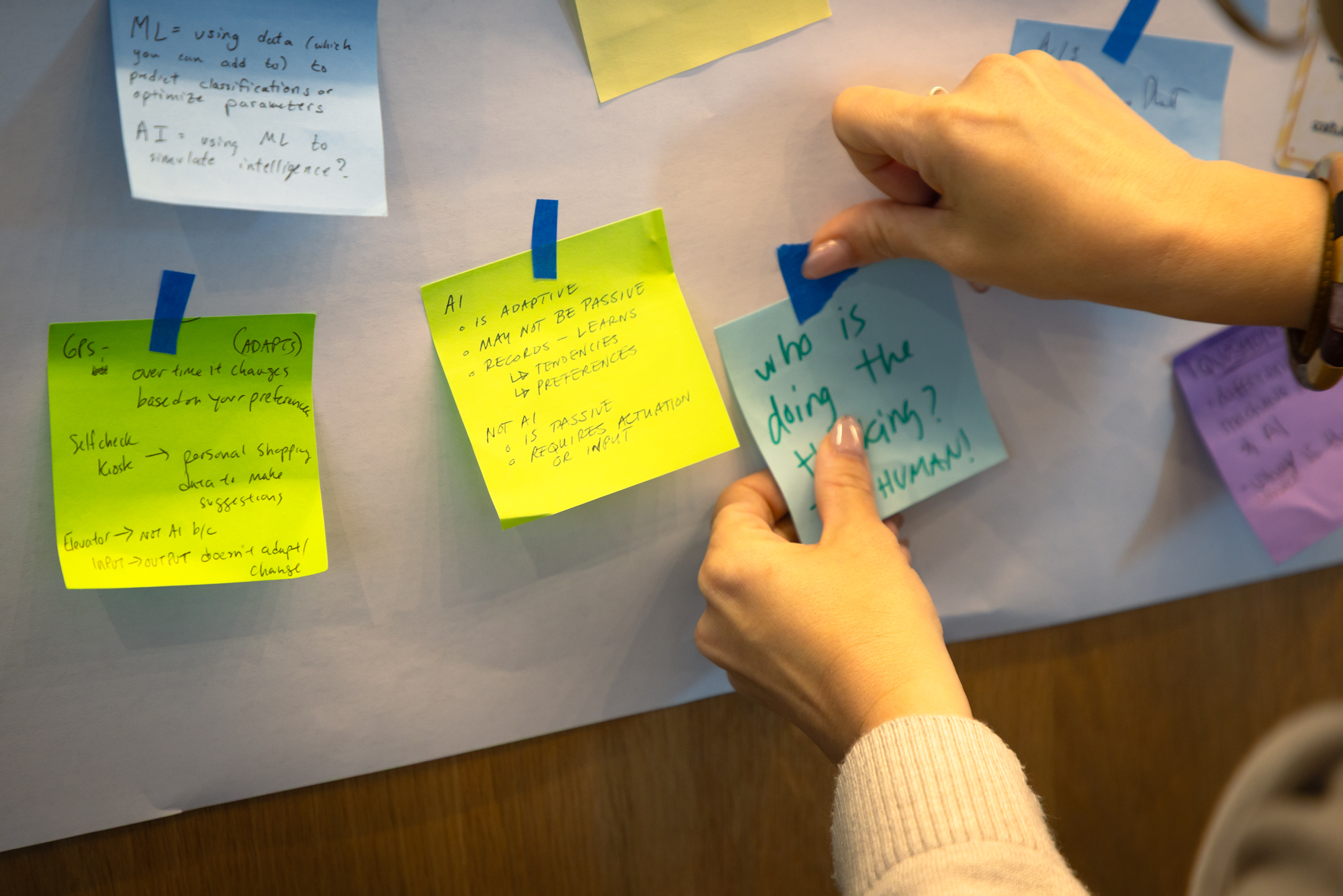 Participant puts up post-it notes at Dora Demszky’s Practitioner Voices Summit