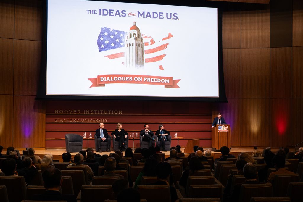 A discussion panel at Stanford University's Hoover Institution, with speakers and an audience in a modern auditorium setting.