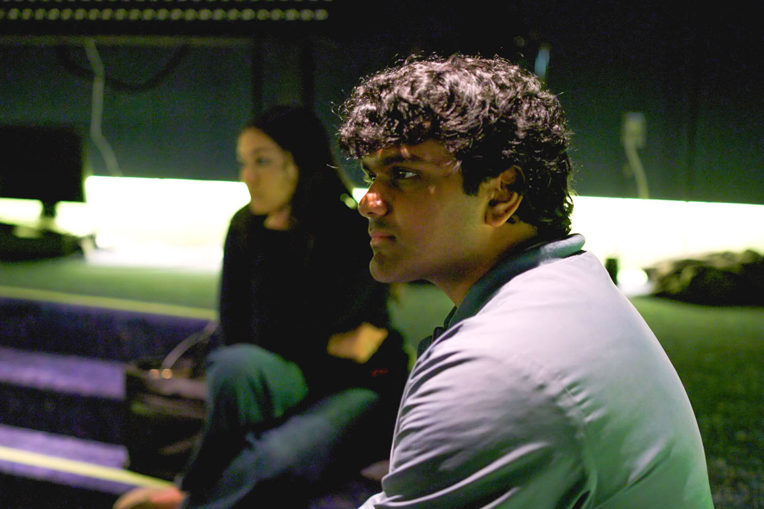 Two students are seated in a dimly lit recording studio.