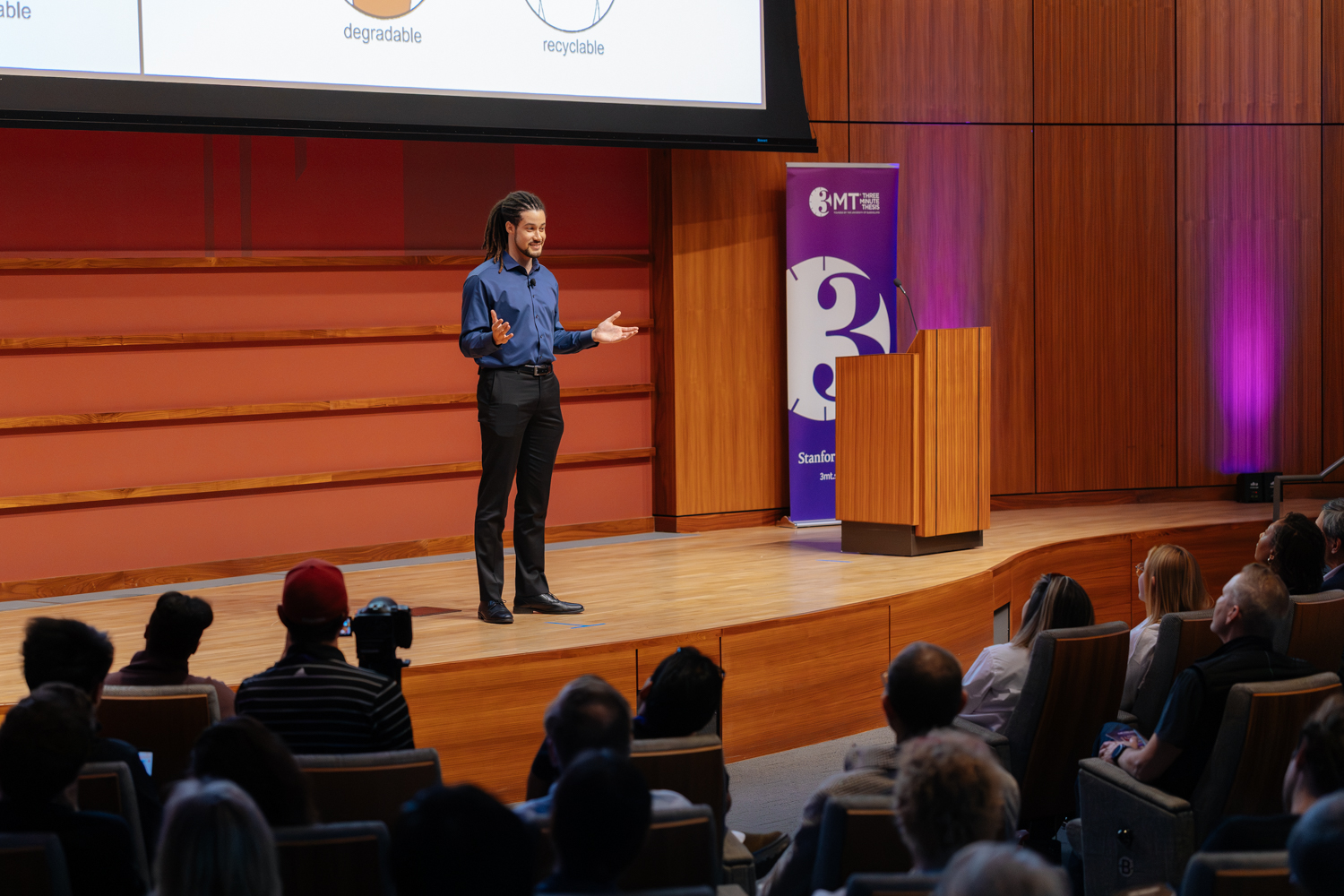 David Dumas presenting on stage at 3 Minute Thesis competition event.