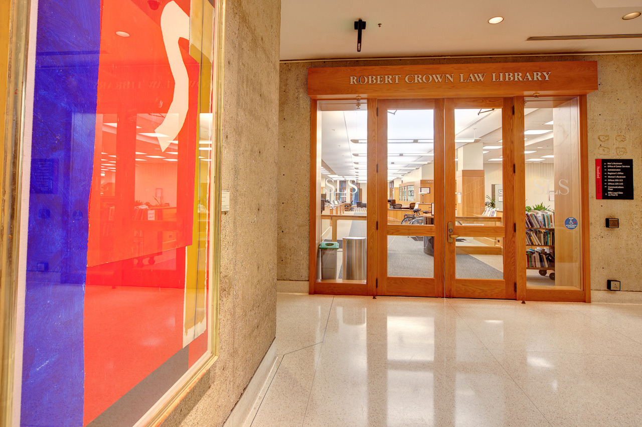 The entrance to the Robert Crown Law Library features wooden doors and colorful artwork on display nearby.