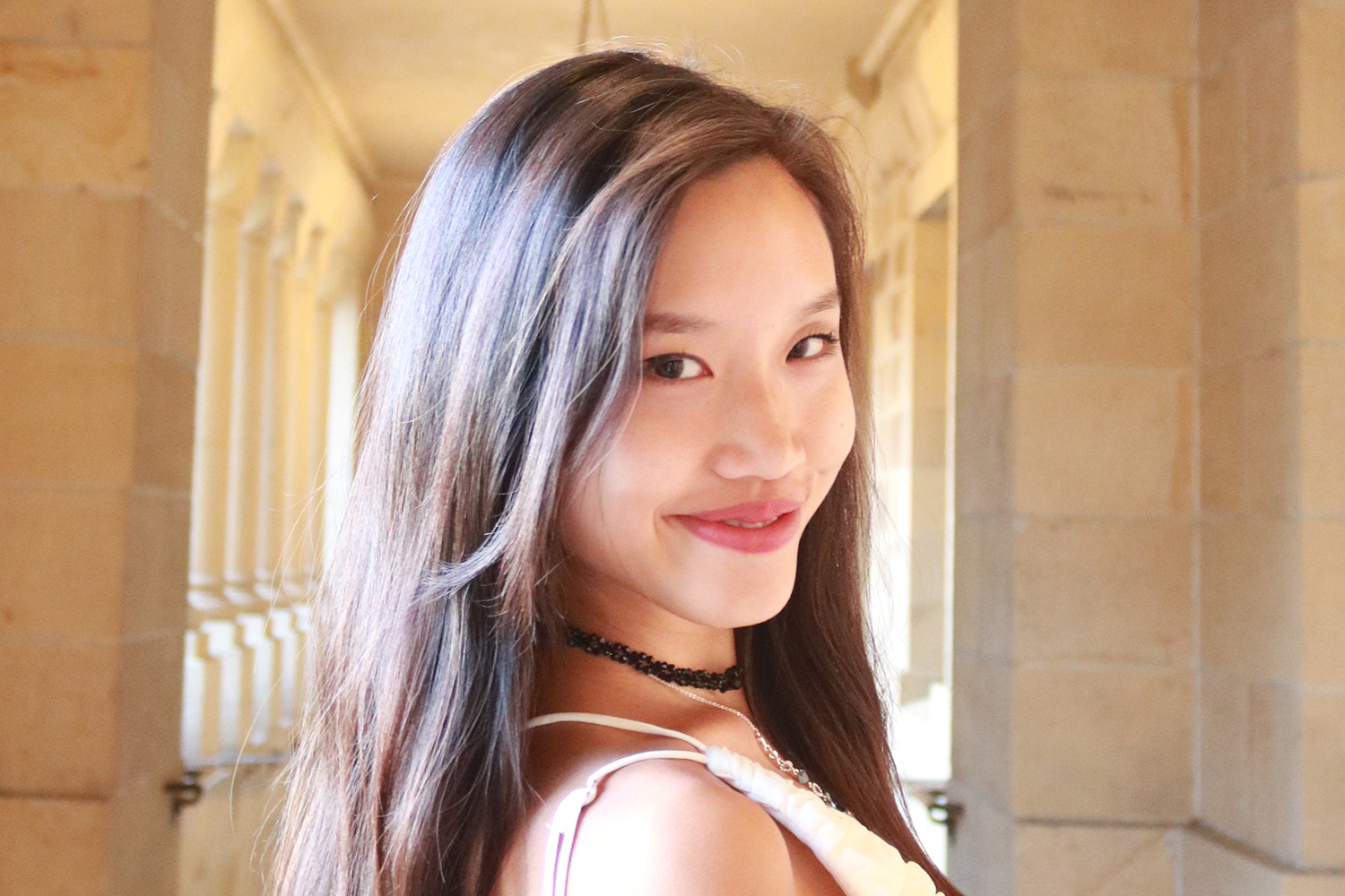 Jessie Ong smiling in a hallway with arched columns.
