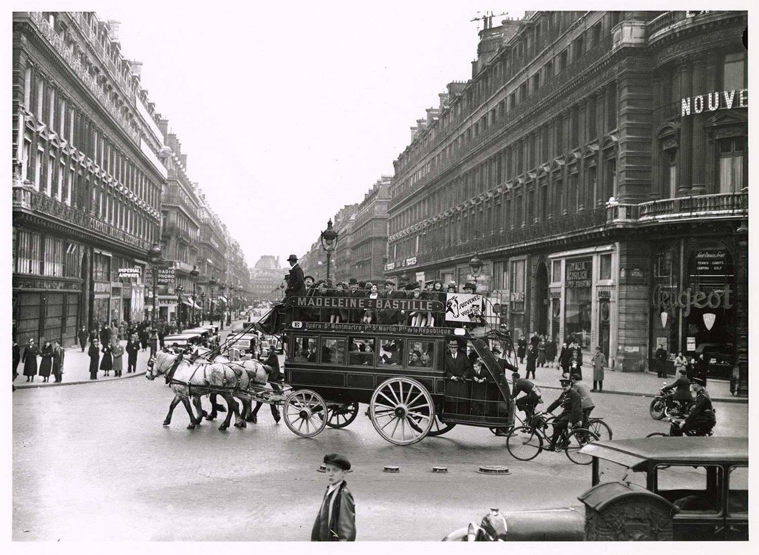 A horse-drawn omnibus carries passengers through a busy Paris boulevard in this early 19th-century photograph.