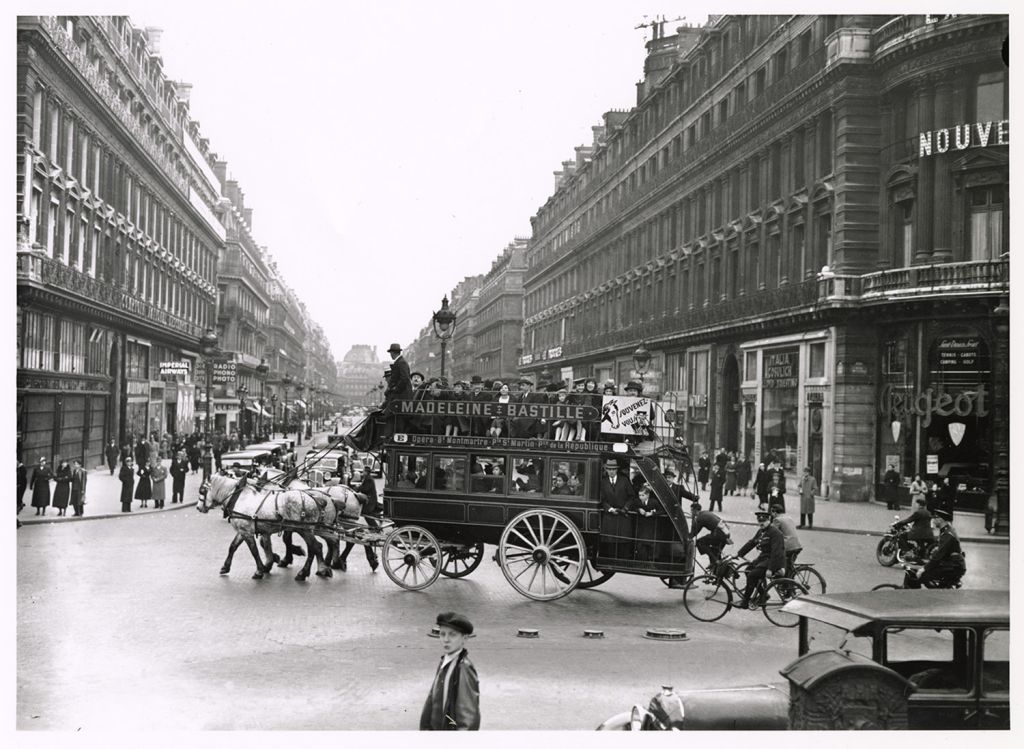 A horse-drawn omnibus carries passengers through a busy Paris boulevard in this early 19th-century photograph.