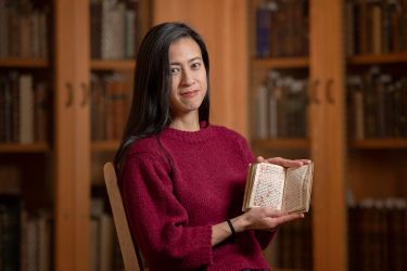 Marisa Galvez, holds a manuscript from Stanford Libraries Special Collections