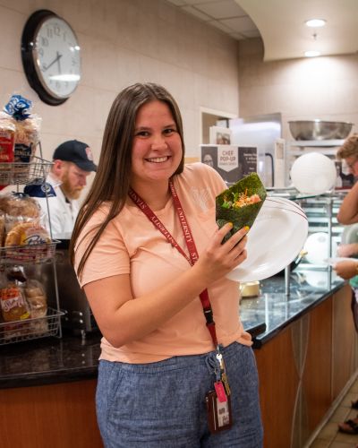 Student holding a roll with sushi.