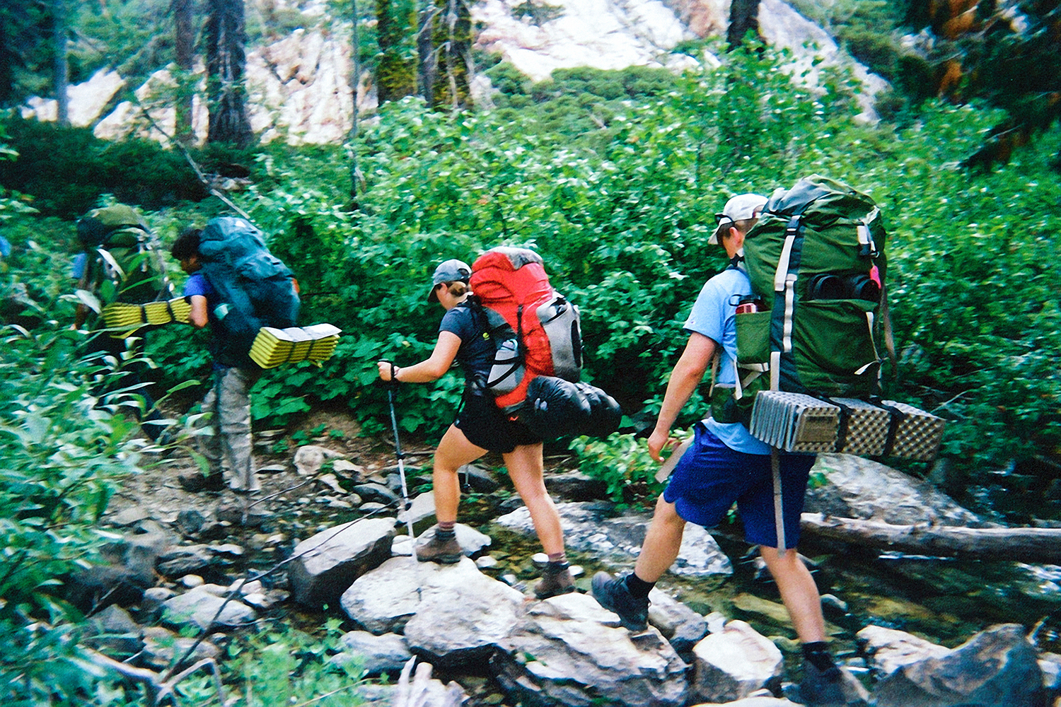 Students backpacking across a creek in the forest.