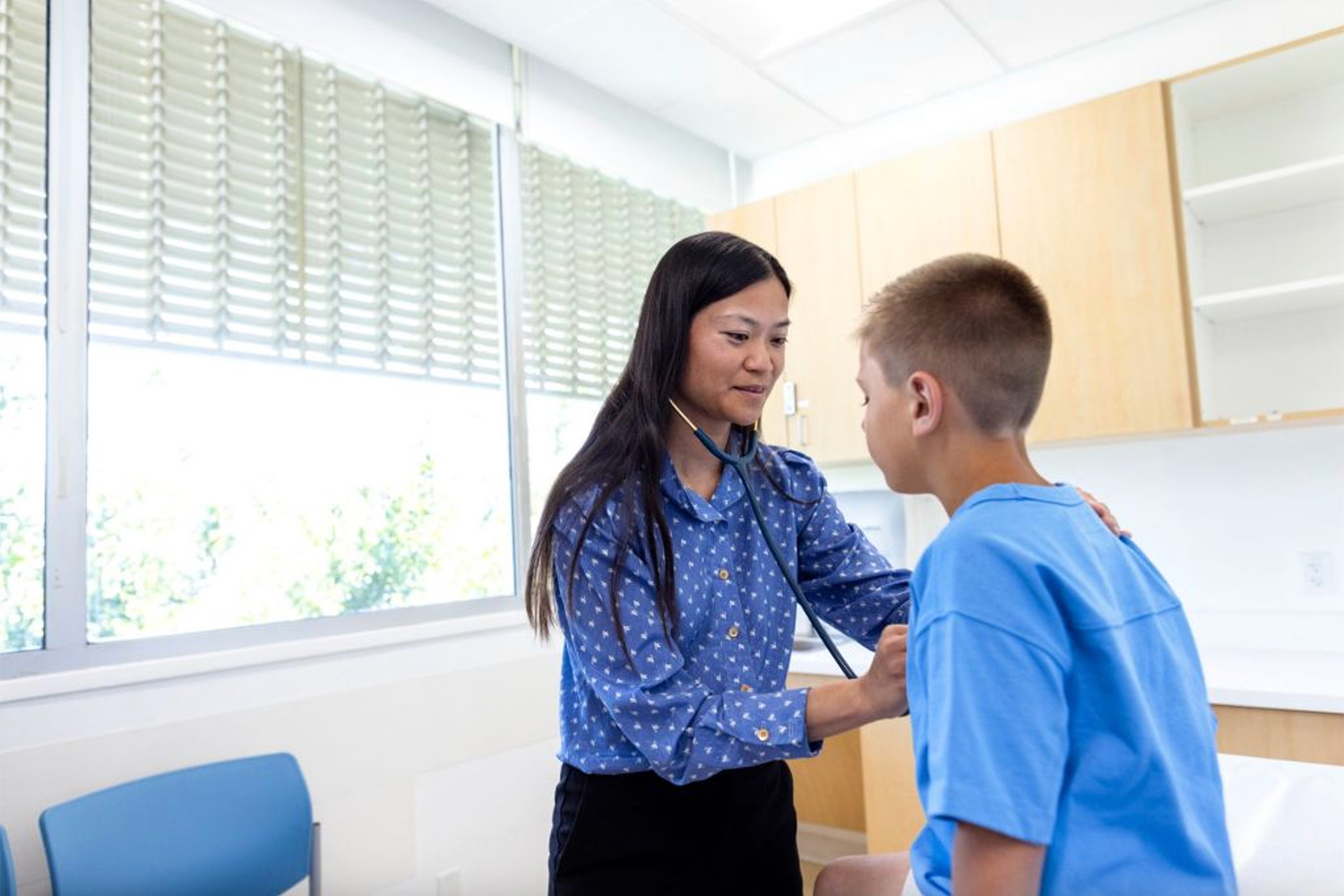 Image of Sophia Giang checking a child's breathing with a stethoscope.