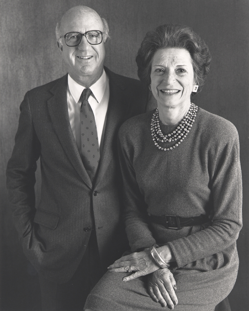 Don and Doris Fisher pose for a formal black-and-white portrait, with him in a suit and her wearing a sweater and pearls.