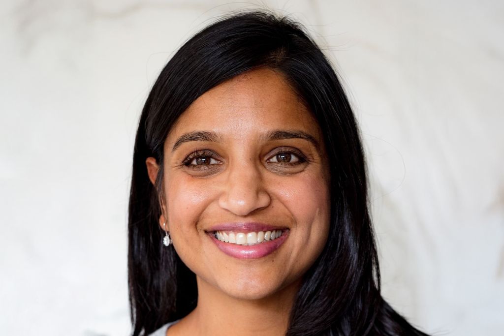 Headshot of Anisha Patel with long black hair in front of a neutral background, looking directly at the camera.