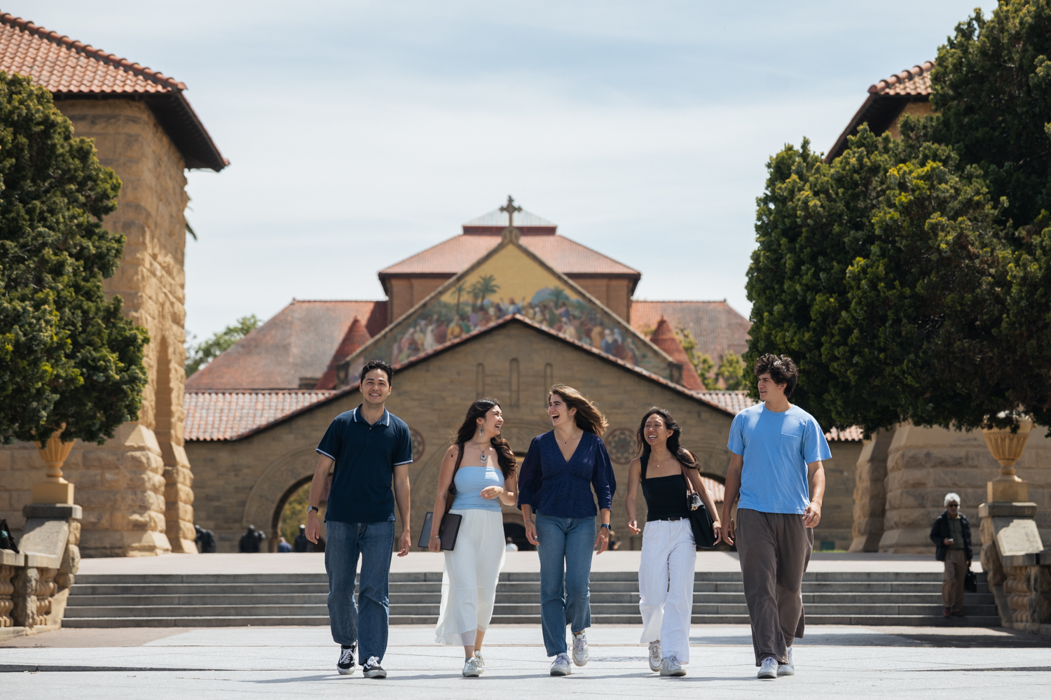 Five friends walk together on a sunny day with Memorial Church in the background.