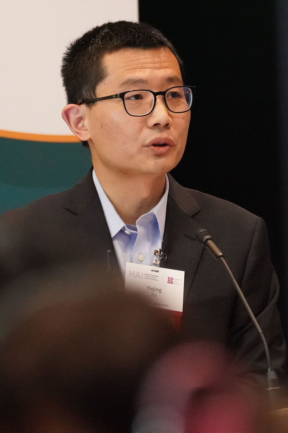 Yiqing Xu addresses an audience while standing at a podium during CORES Symposium.