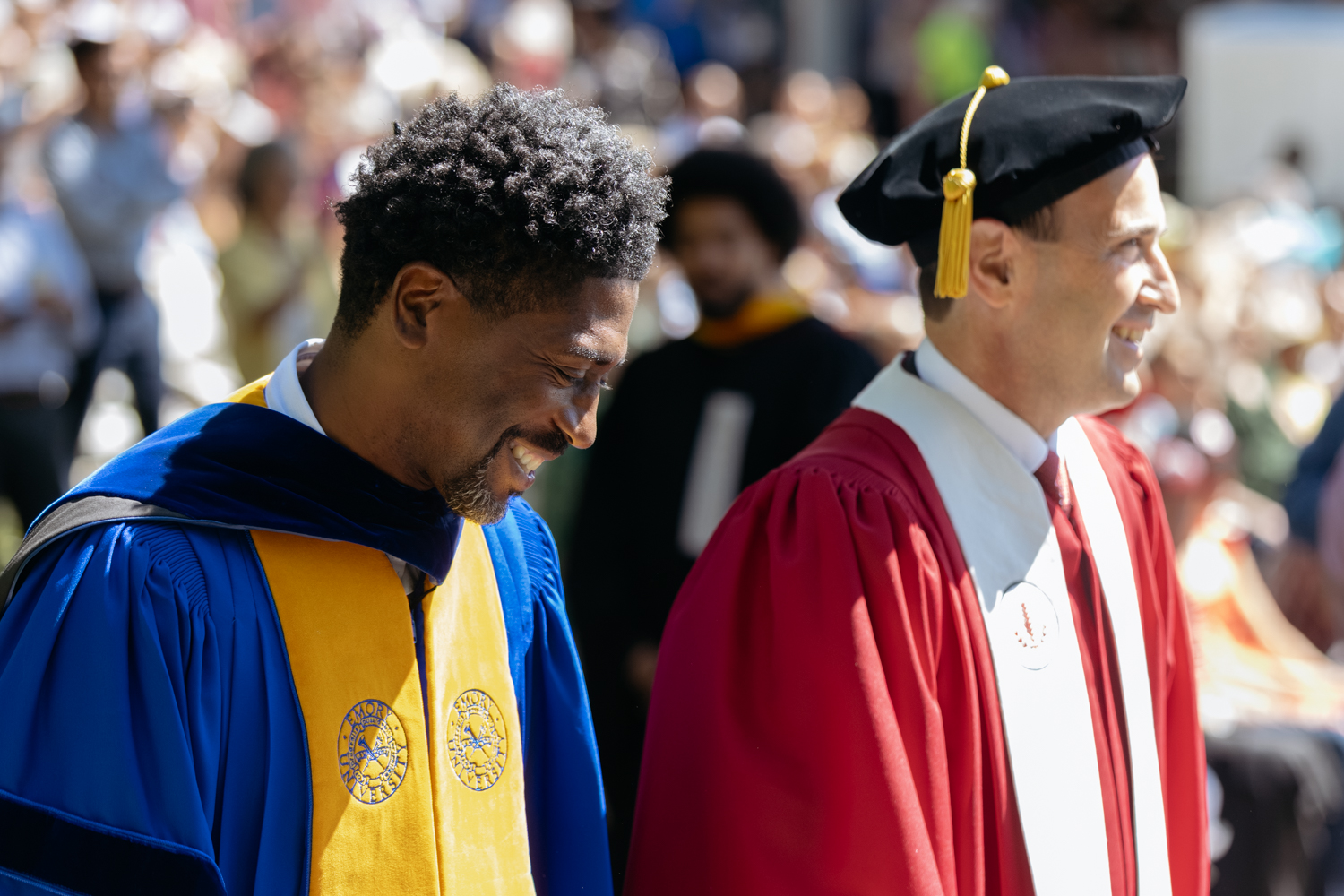 Lerone Martin and President Jon Levin walk together during Baccalaureate, with an audience visible in the background.
