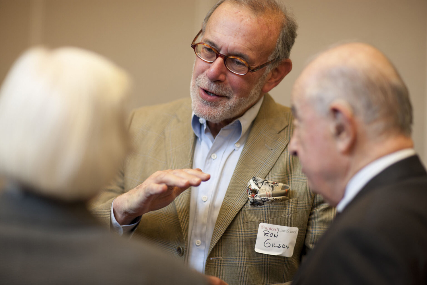 Ronald Gilson gestures while speaking with two colleagues.