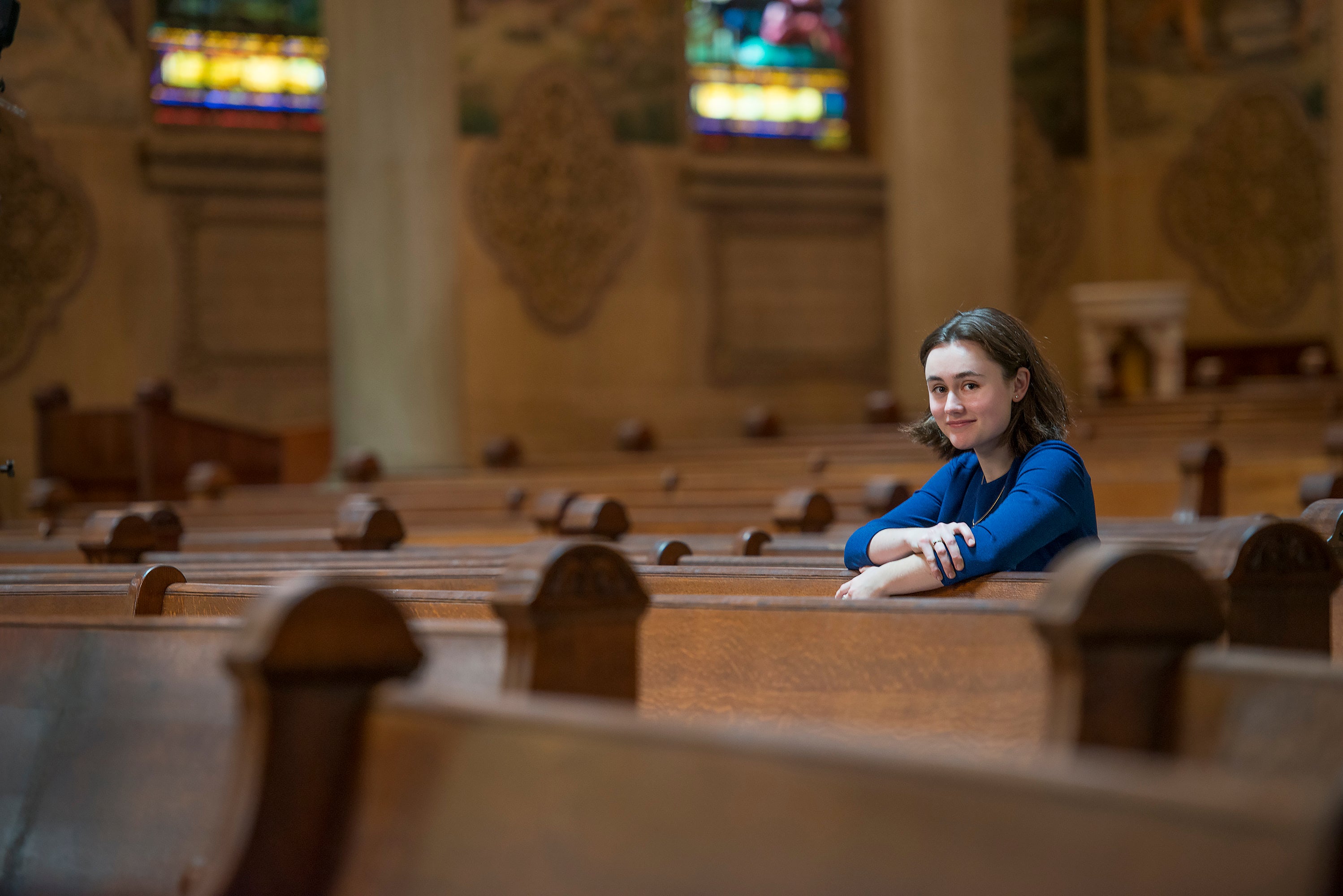 Student Christina E.C. Smith photographed among the pews in Memorial Church. (Smith studies medieval wood carvings called misericords.)