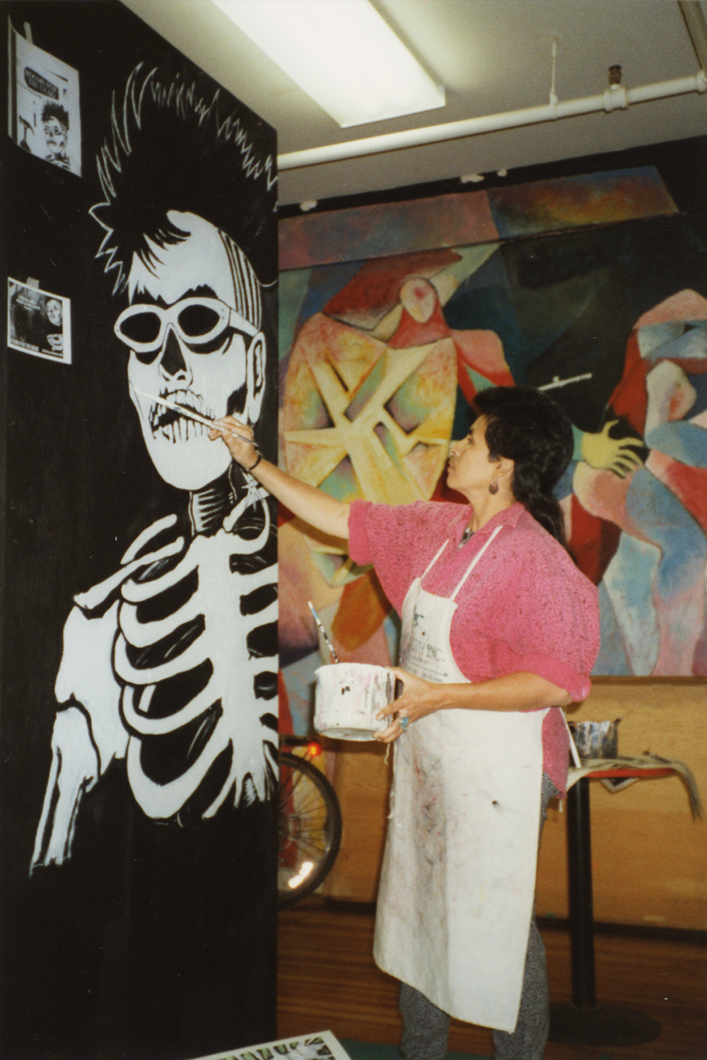 Ester Hernandez paints skeleton figure at Mission Cultural Center, Day of the Dead, 1992.
