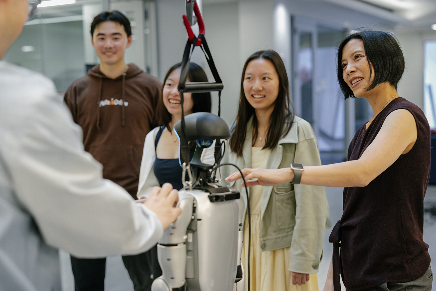 A group of people observing a humanoid robot during a demonstration in a modern setting.
