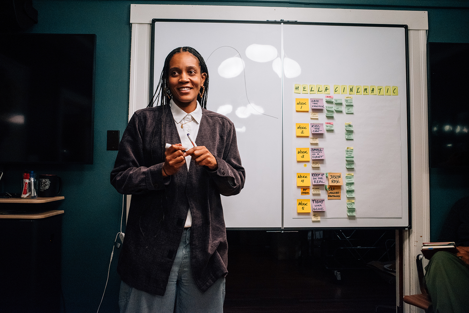 A presenter shares ideas while standing in front of a whiteboard covered with colorful sticky notes.