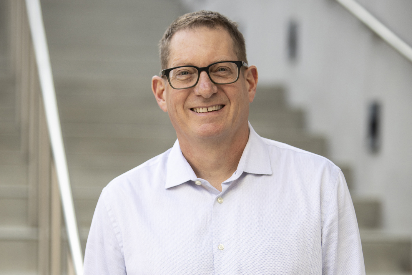 Aaron Straight wearing glasses and white shirt smiling at camera.