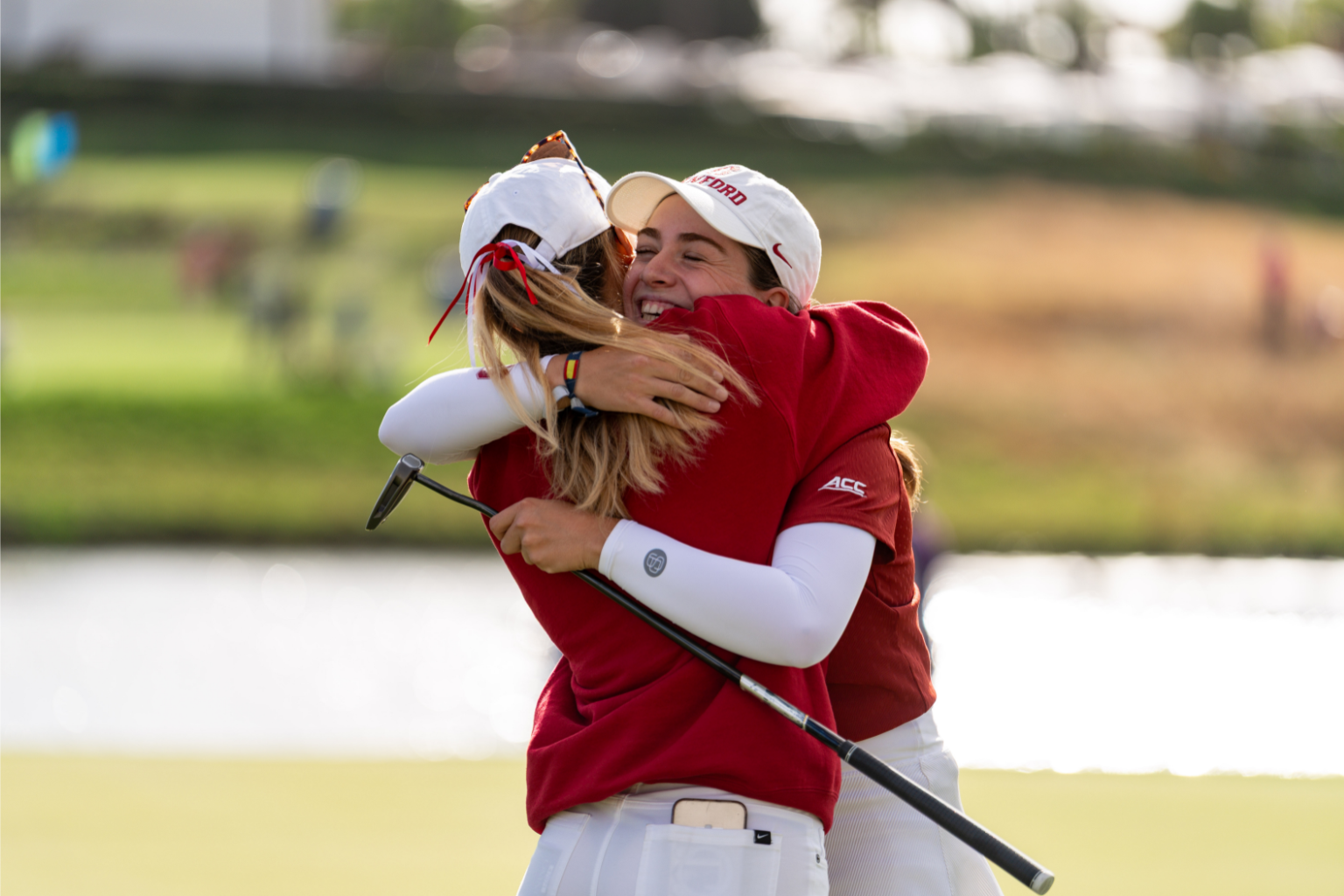 Two women's golf players embrace after winning the NCAA championship