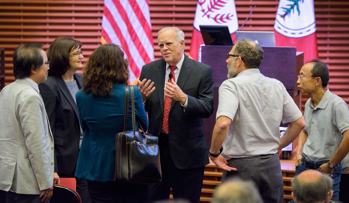 John Hennessy surrounded by faculty members.