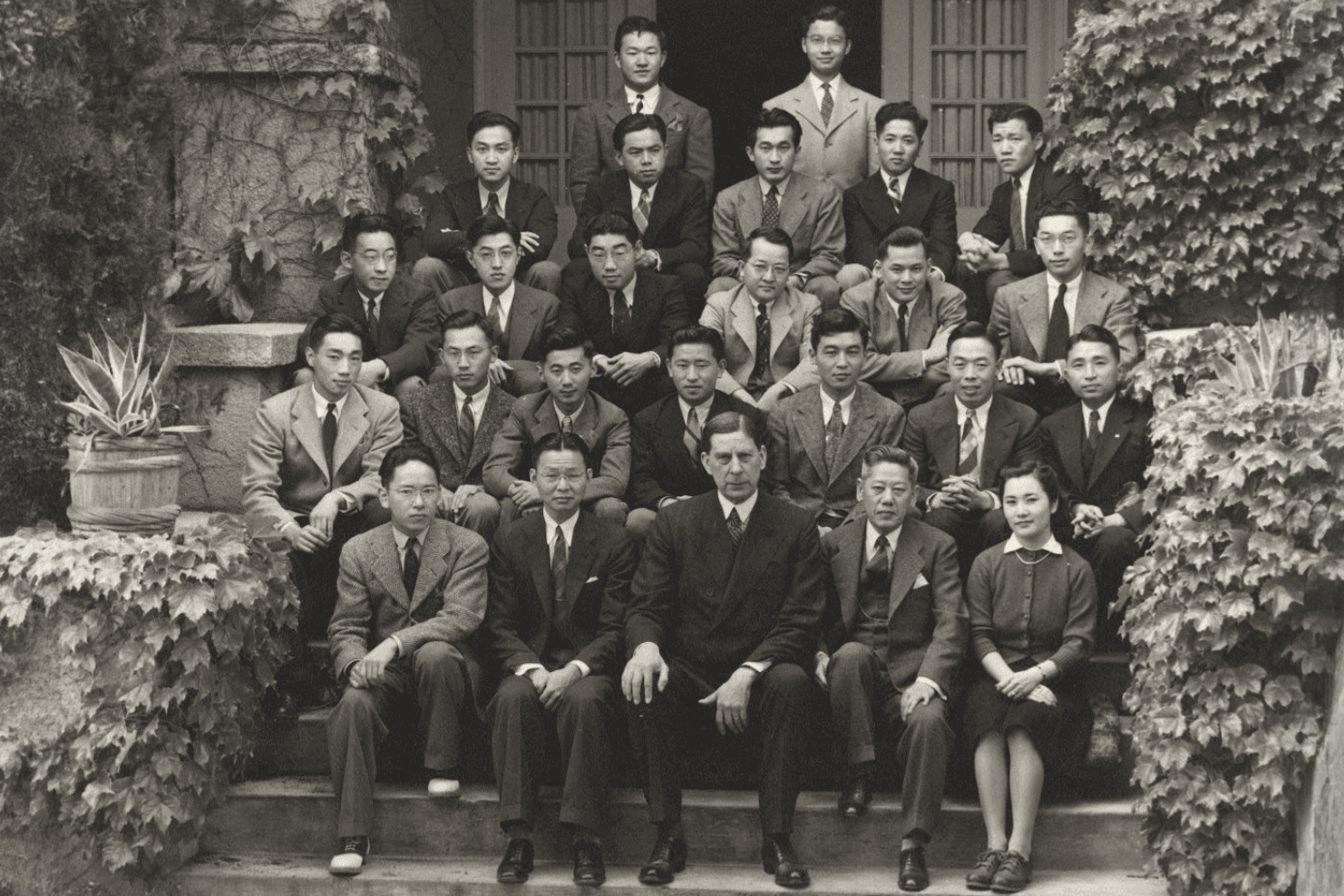 Group portrait of the Stanford University Japanese Association members seated on steps, surrounded by greenery, taken on May 13, 1941.