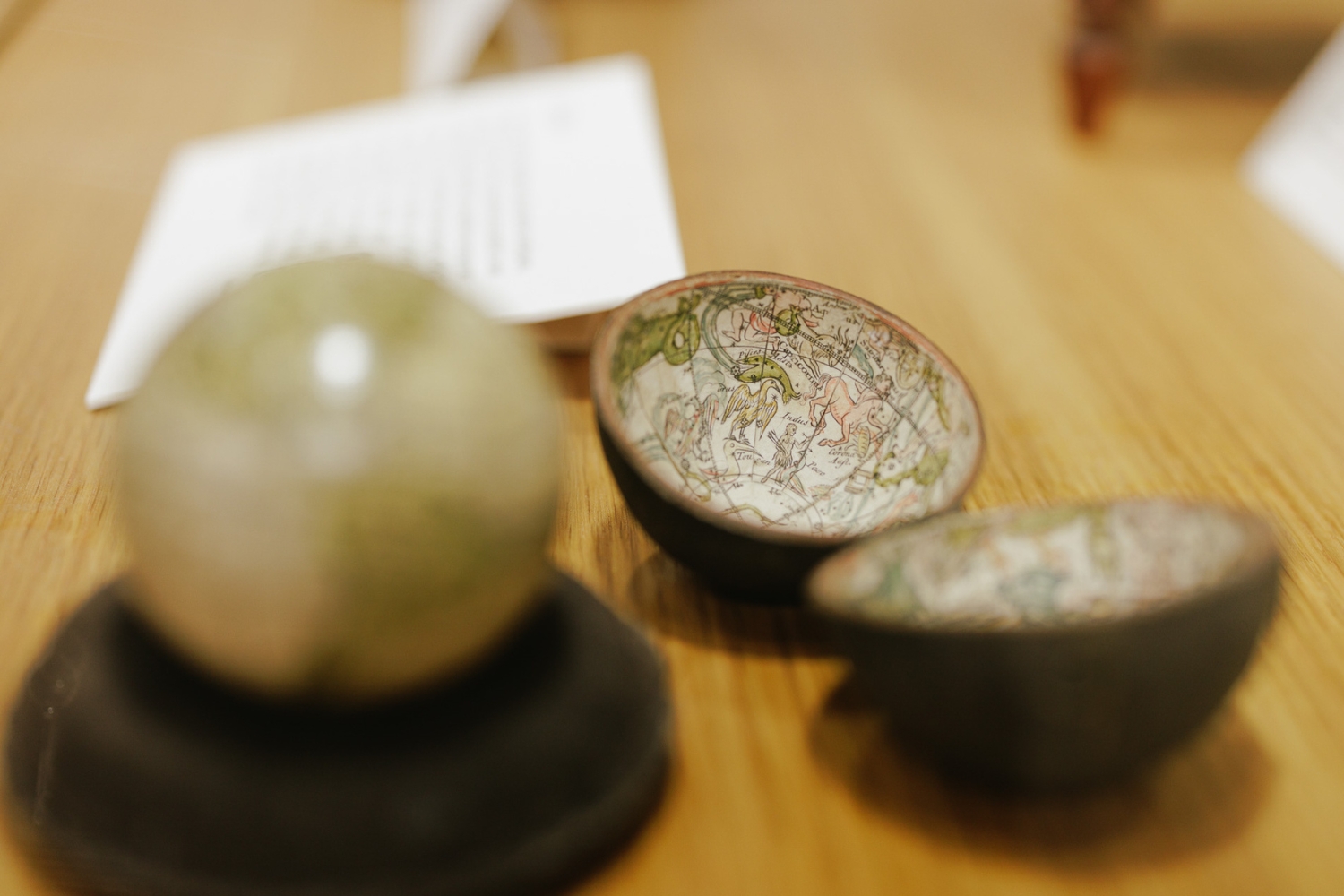 A small globe and two globe-shaped bowls displaying colorful maps rest on a wooden table.