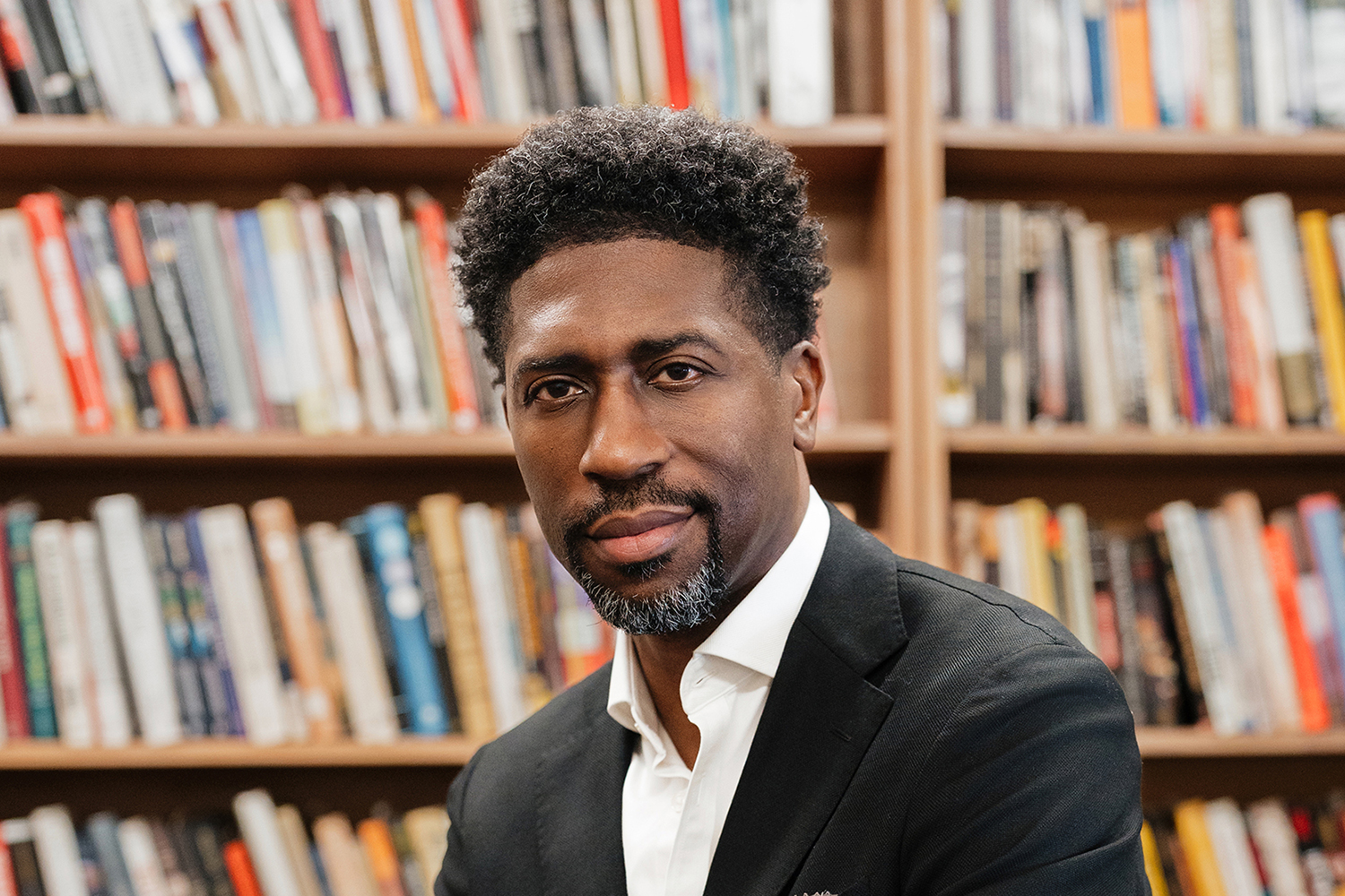 Lerone A. Martin posing for a photo and seated in a library setting.