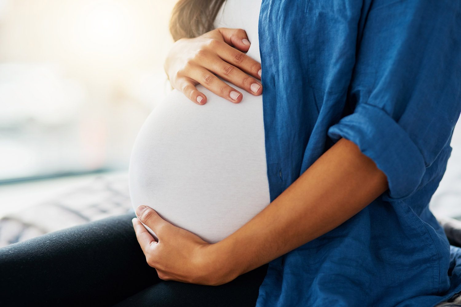 Closeup shot of an unrecognizable pregnant woman holding her belly.