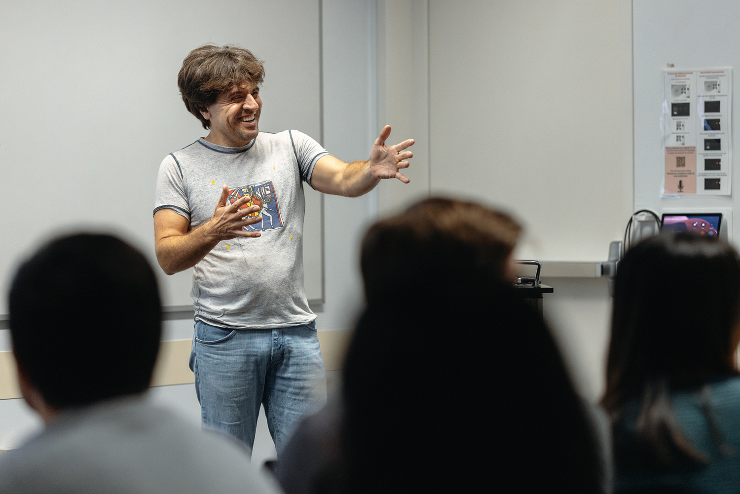 Karl Deisseroth gestures with both hands while speaking to an audience seen from behind.